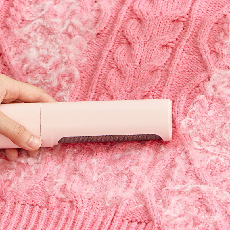 Reusable pet hair remover roller used on pink fabric
